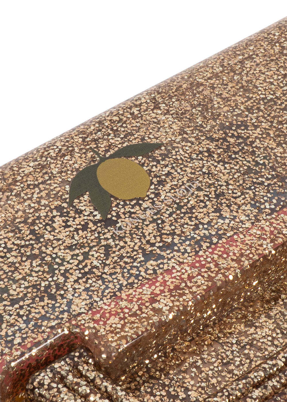 Close-up of a textured clutch or envelope-style handbag with a dense gold and beige speckled pattern, a small dark green leaf motif, and a gold oval accent on a white background.
