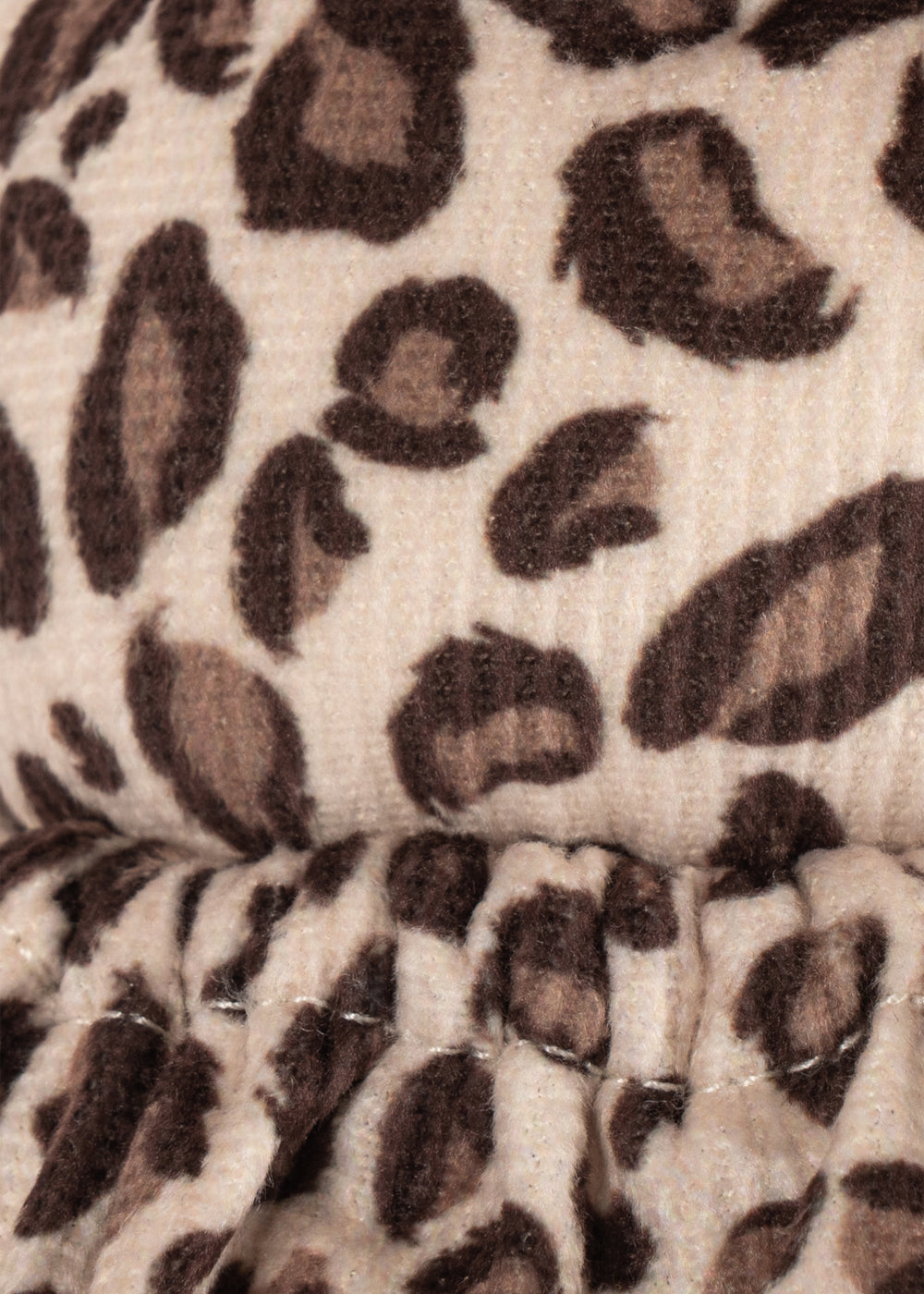 Close-up of leopard print fabric with brown and black spots on a beige background