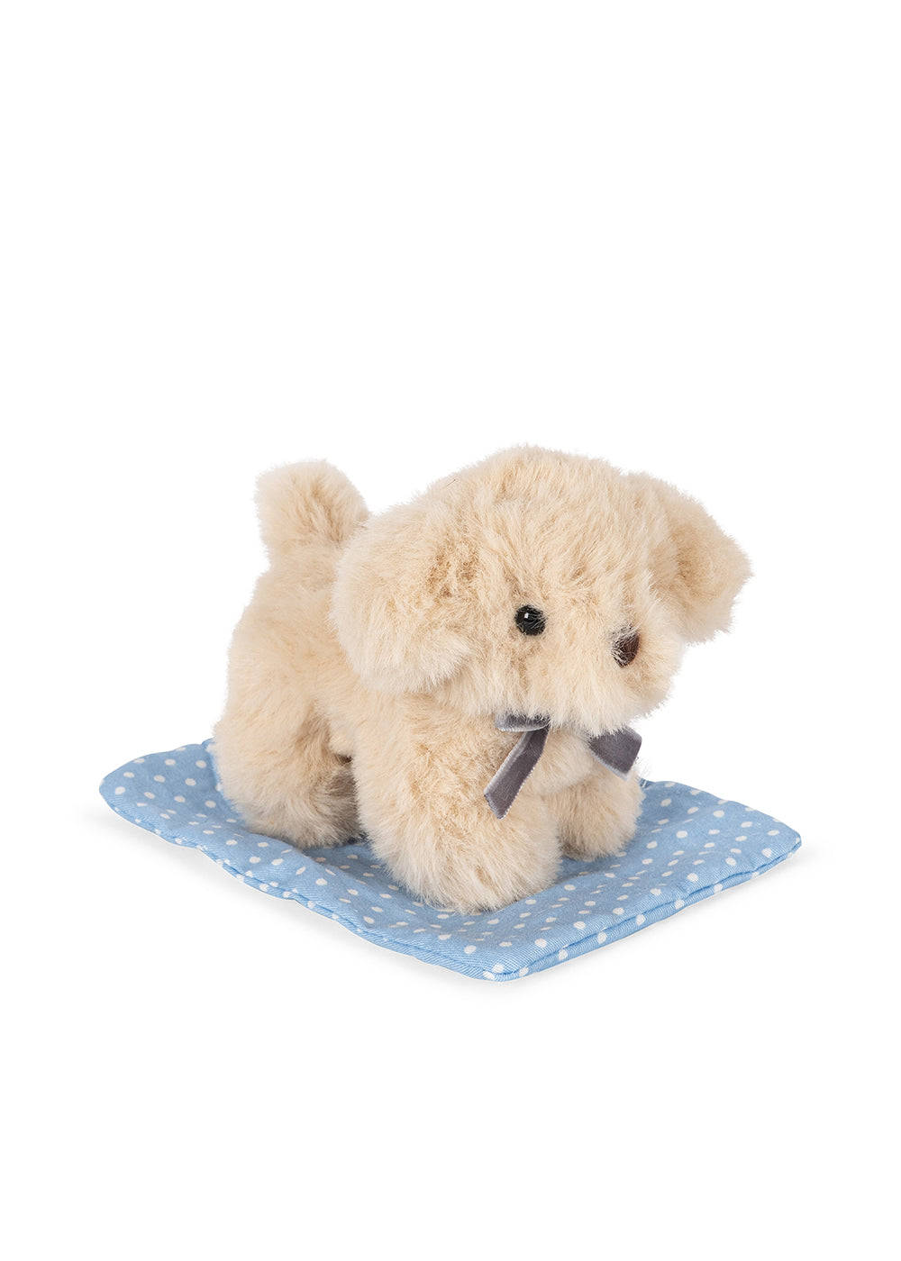 Plush dog toy on a blue polka dot mat with a white background