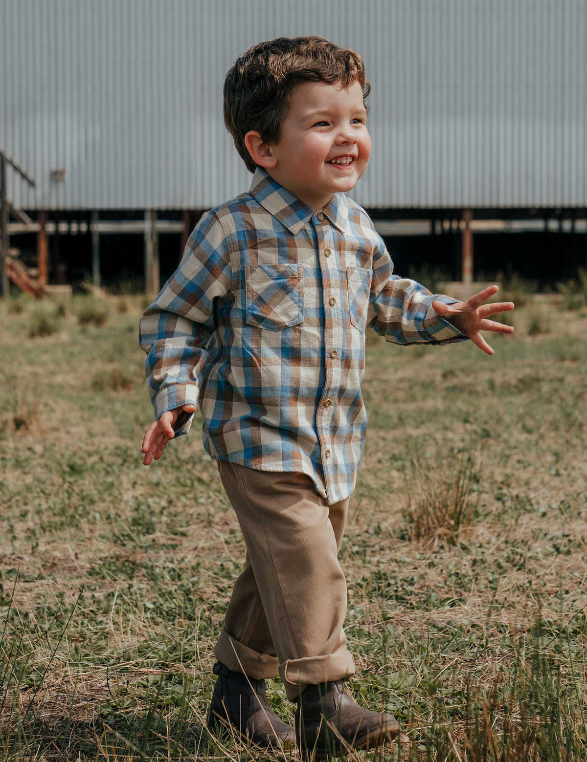 Child in a plaid shirt and jeans standing in a field
