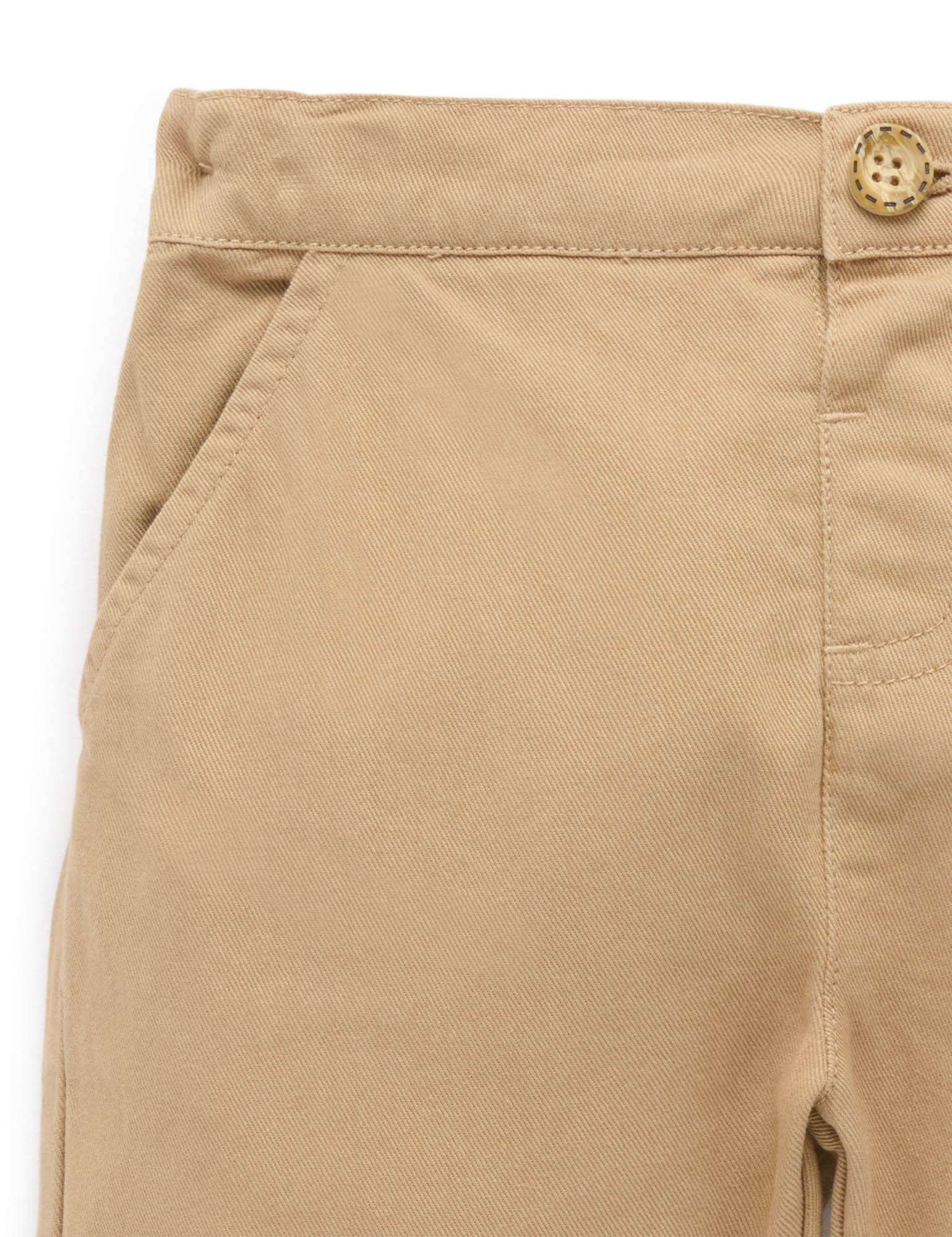 Close-up of beige pants with a button on a white background