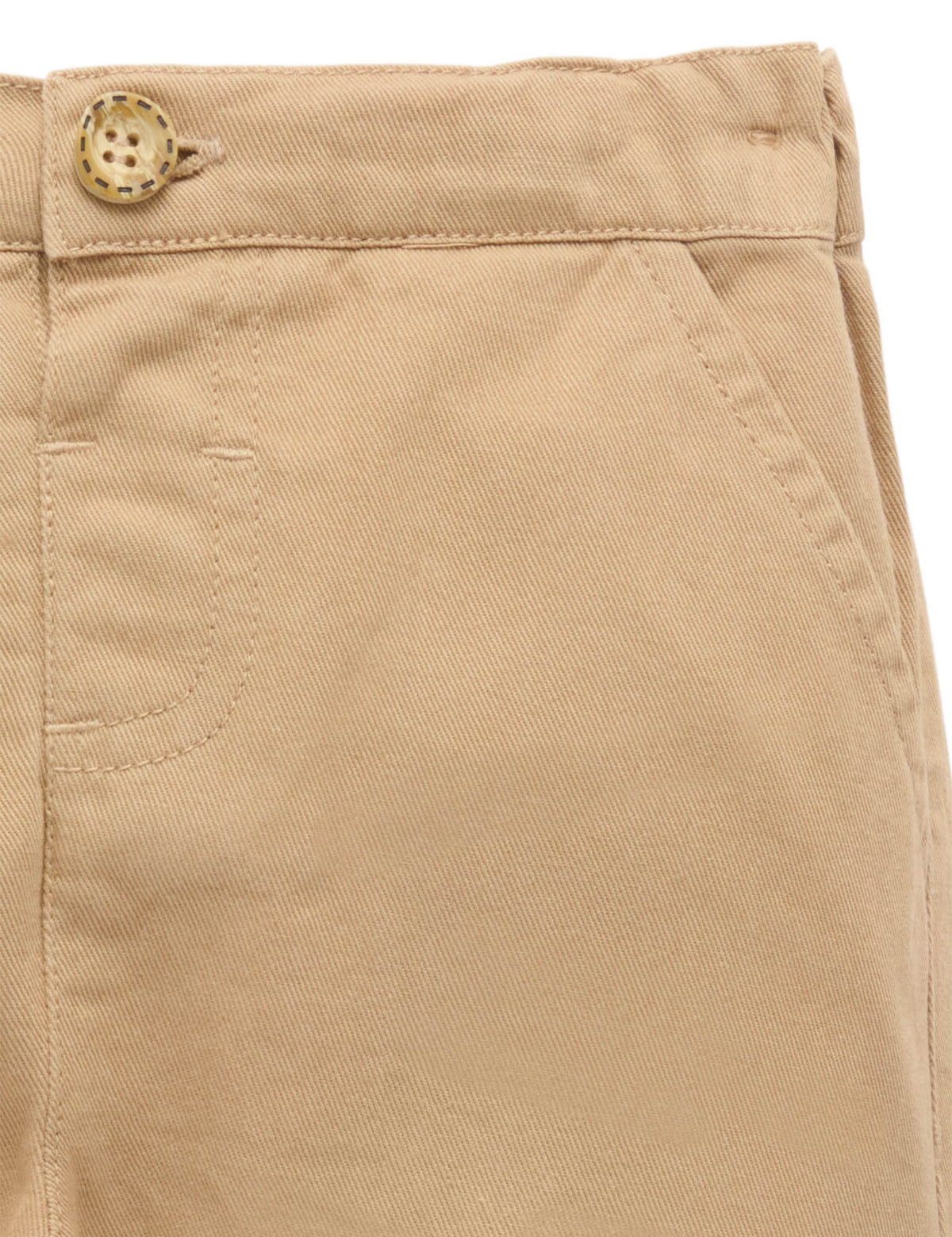 Close-up of beige pants with a button on a white background