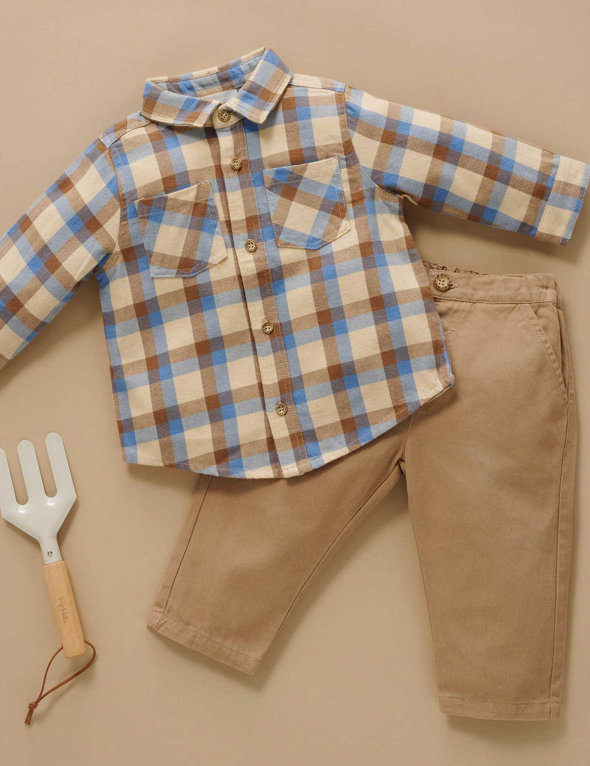Plaid shirt and beige pants with a garden fork on a beige background