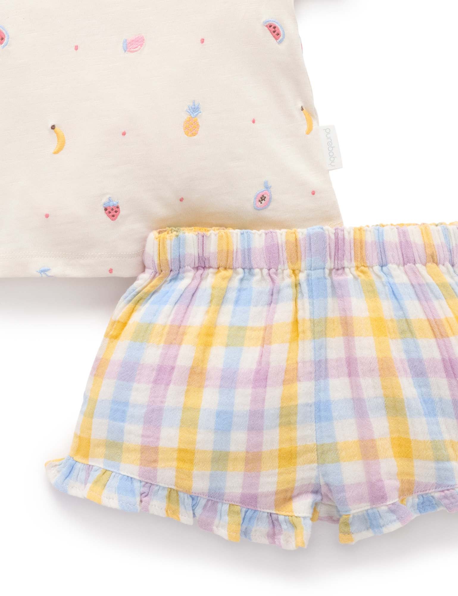 Pastel checkered shorts with a colorful pillow in the background