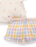 Pastel checkered shorts with a colorful pillow in the background