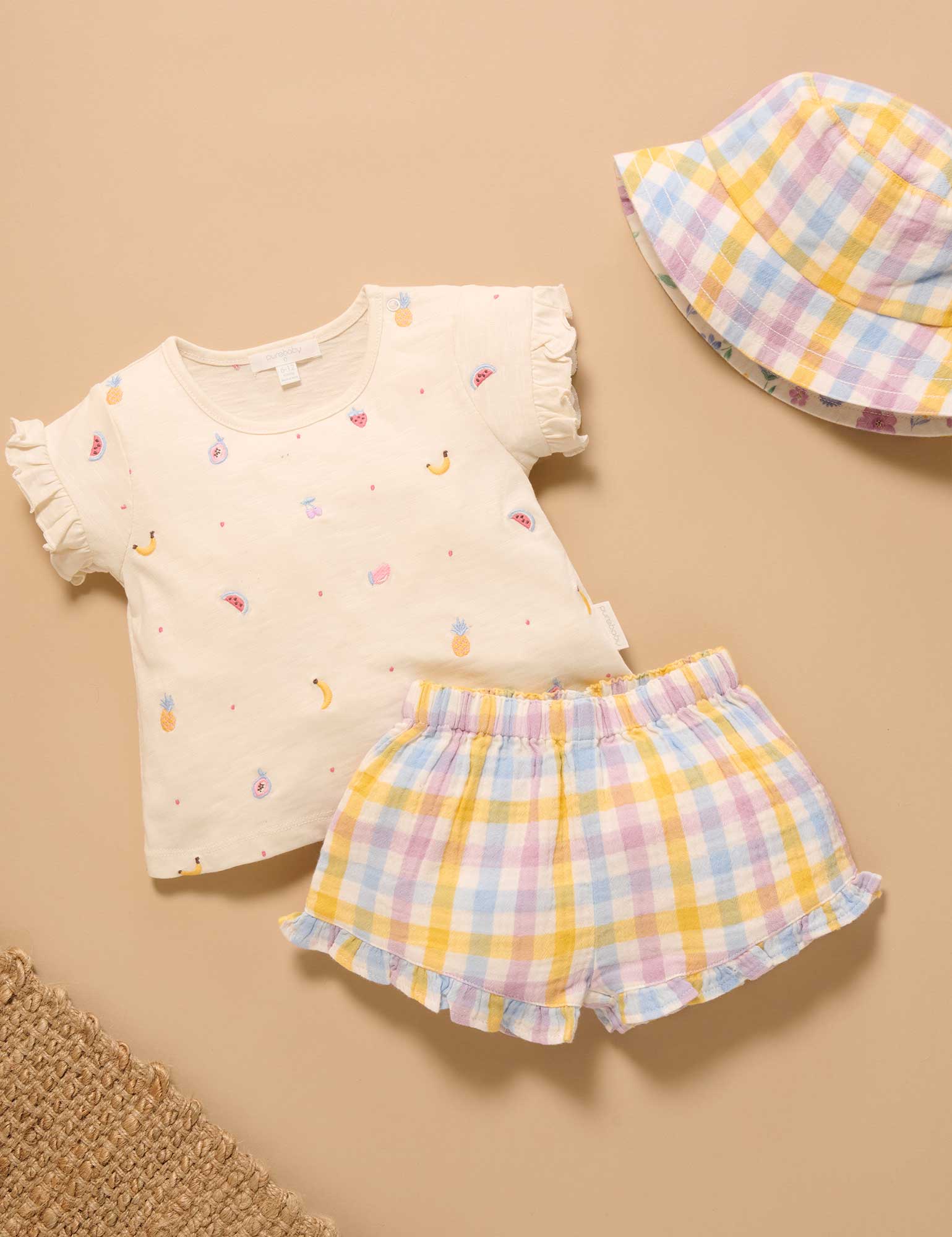 Children's outfit with a top, shorts, and hat on a beige background