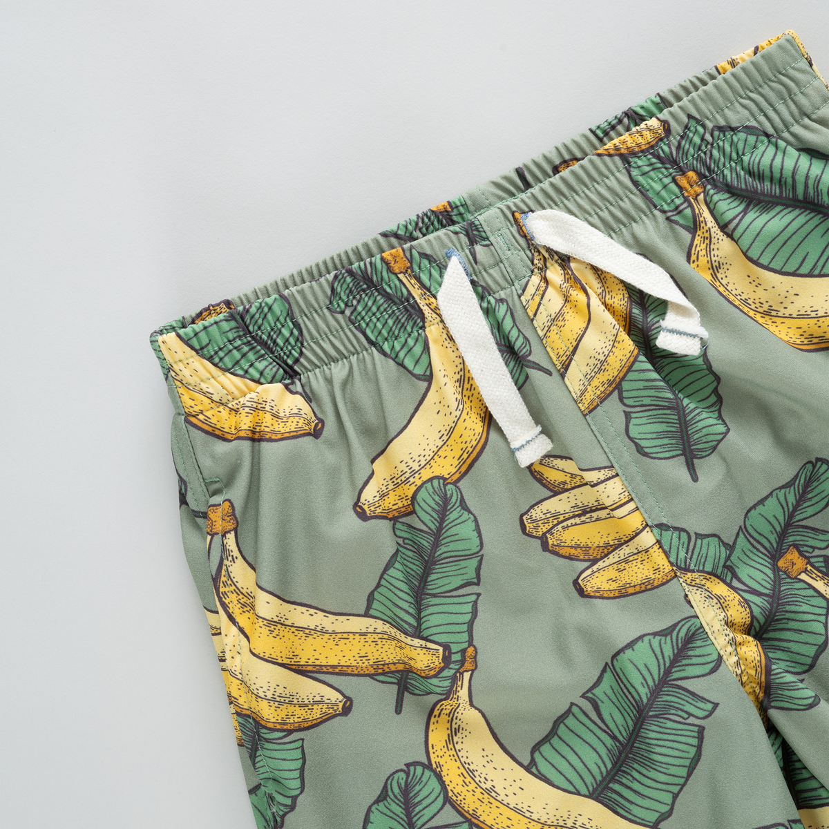 Green shorts with banana pattern on a light gray background
