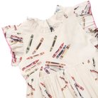 A close-up of a cream-colored children's dress with a colorful crayon print and ruffled sleeves, shown on a plain white background.