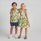 Two children wearing banana-patterned outfits on a plain background