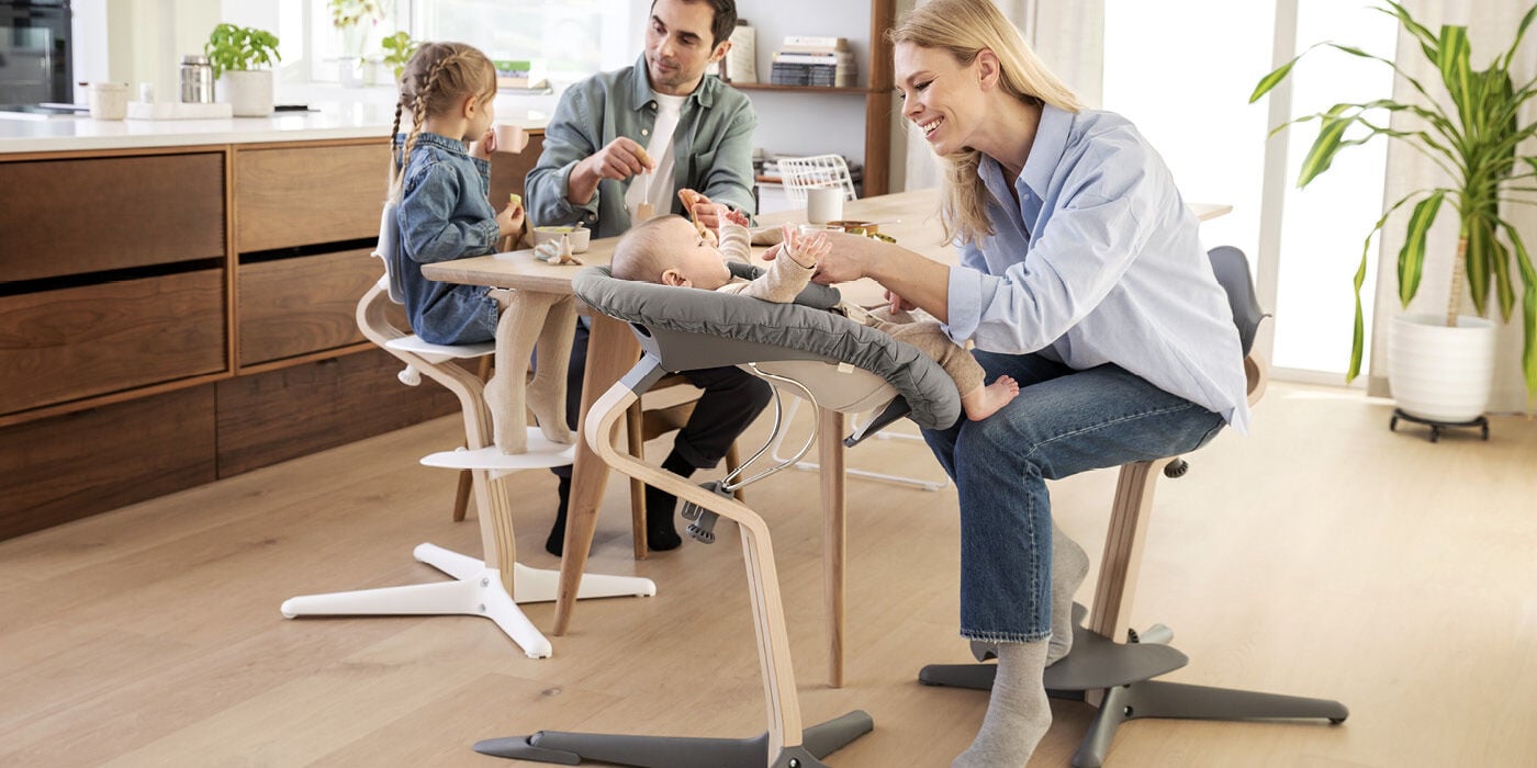 Family sitting at a table with children using adjustable height chairs in a modern kitchen.