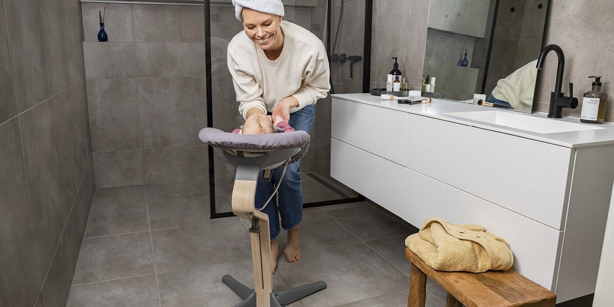 Person using a standing ironing board in a bathroom setting