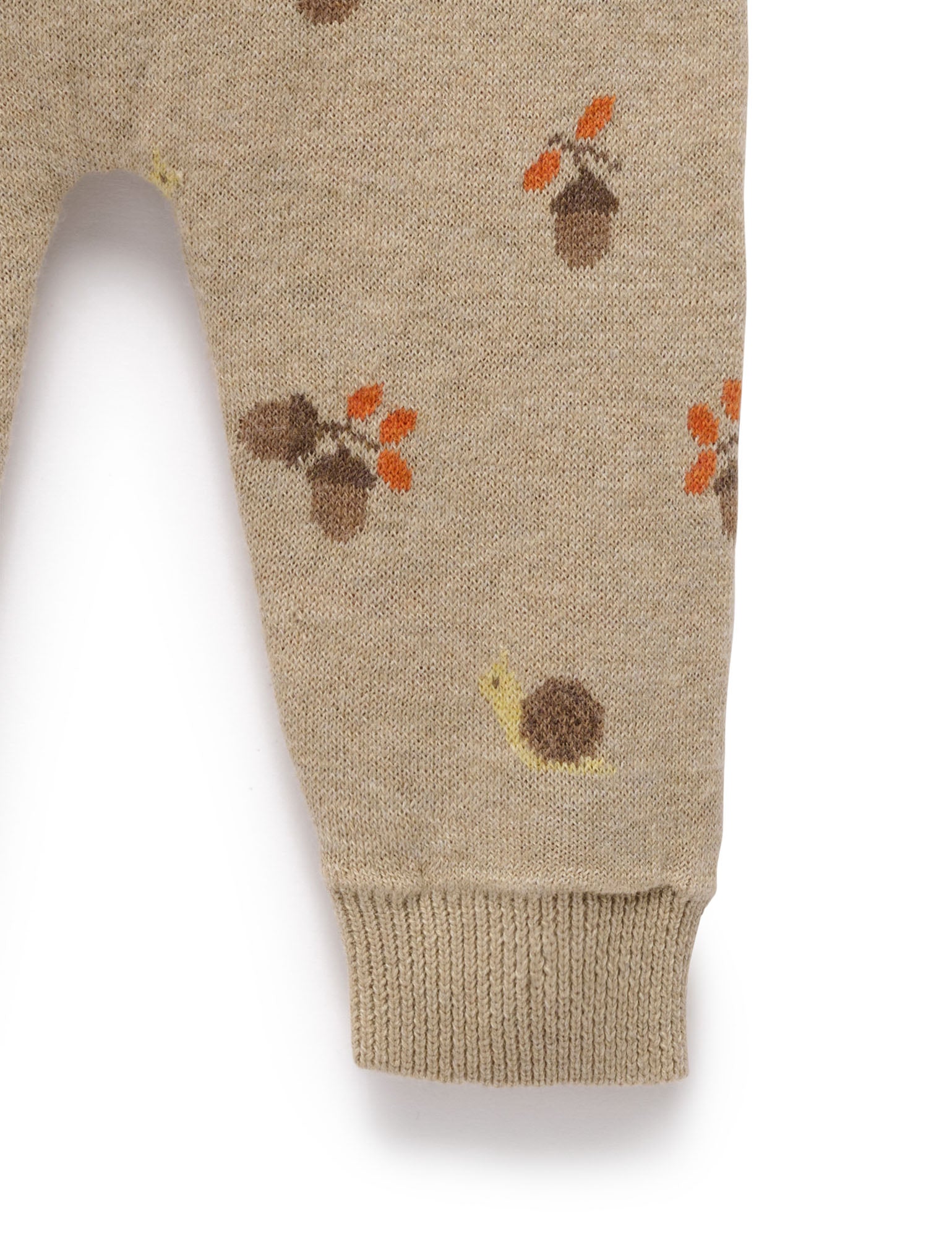 Beige knitted pants with autumn-themed patterns on a white background