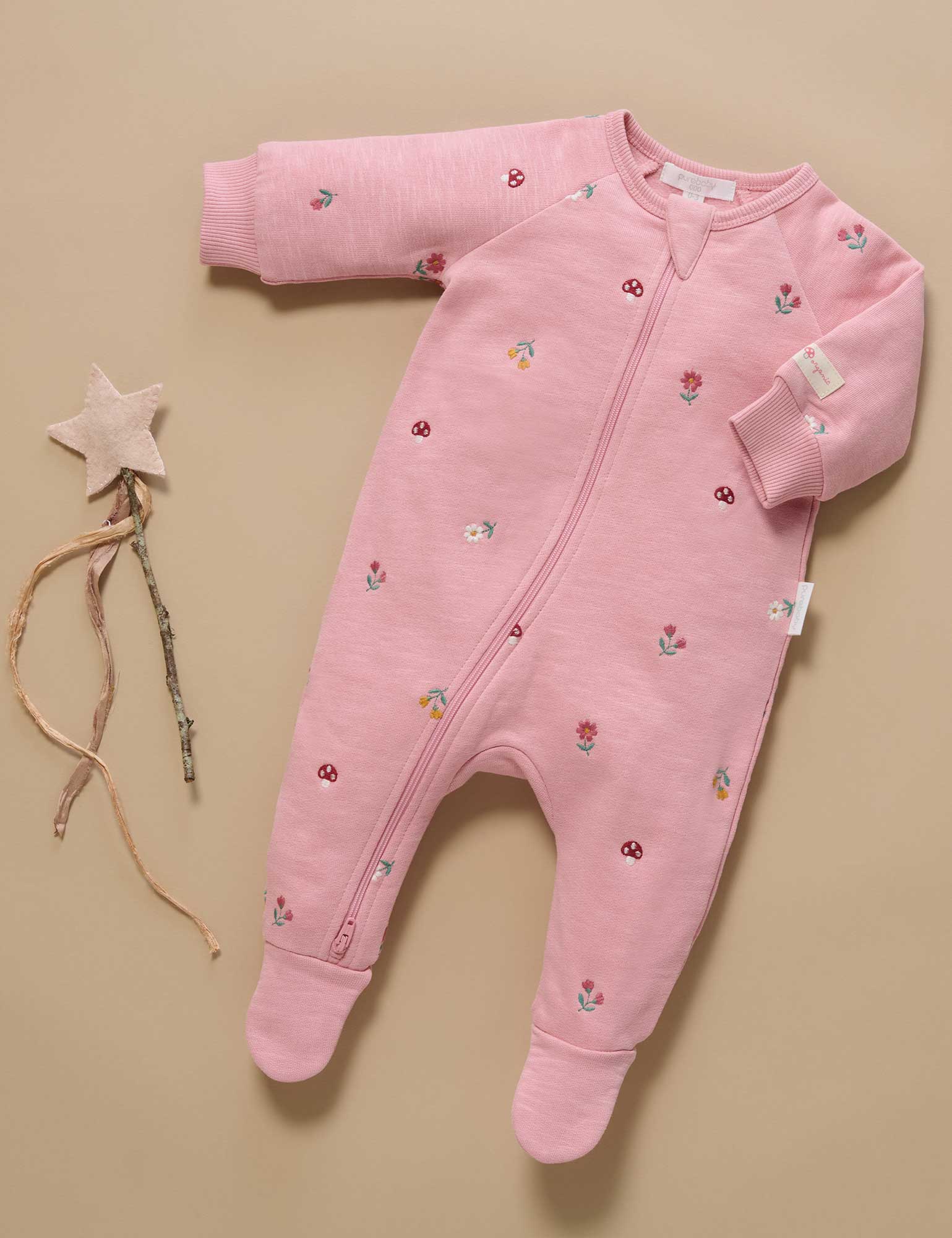 Pink baby onesie with floral patterns on a beige background