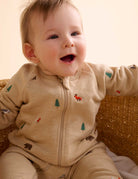 Baby wearing a beige outfit with animal prints sitting in a wicker basket.