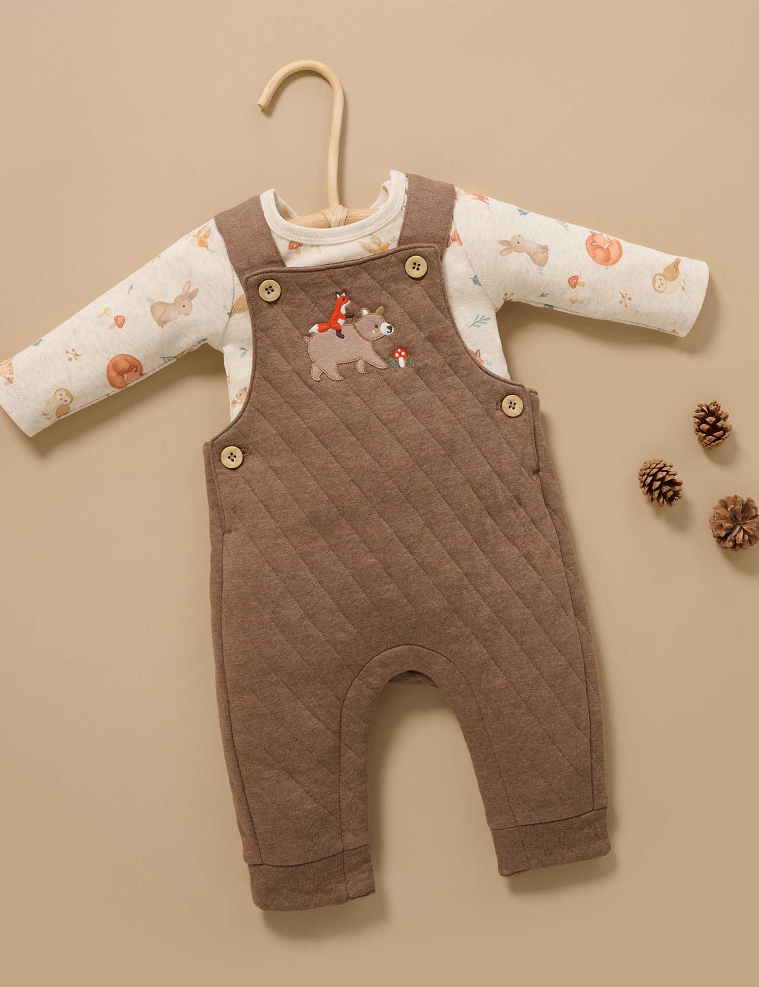 Brown quilted baby romper with animal patterns on a beige background
