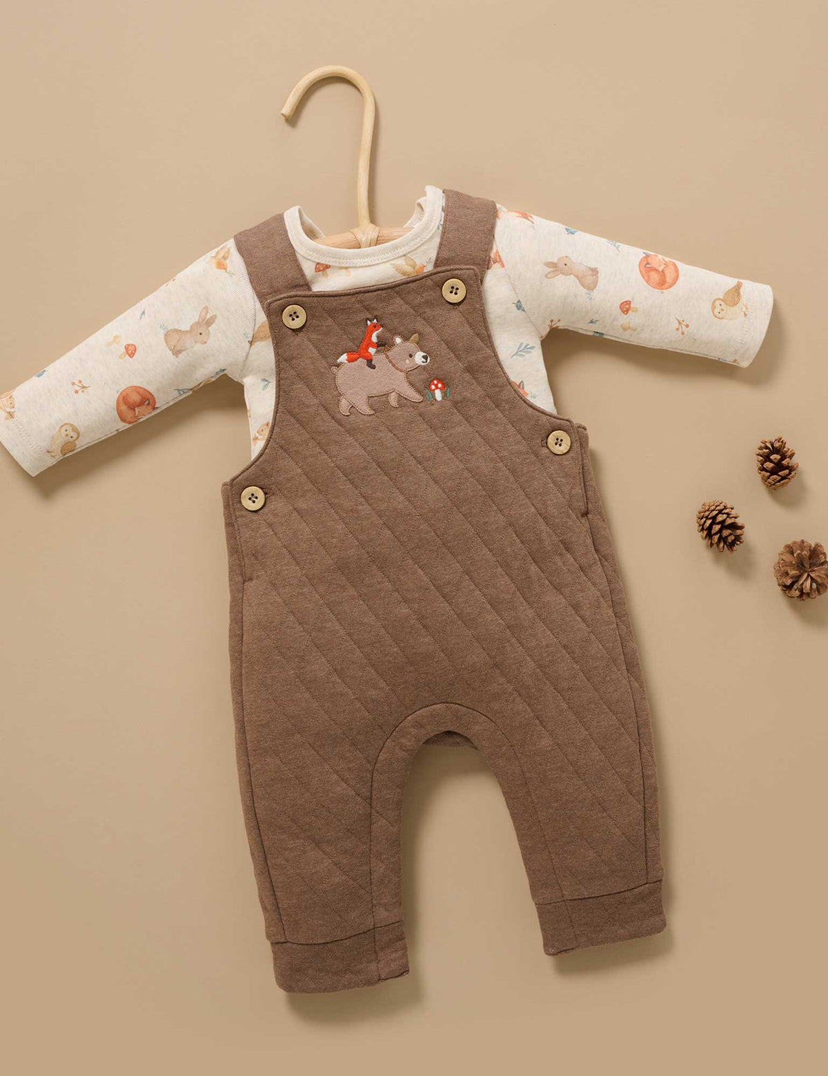 Brown quilted baby romper with animal patterns on a beige background