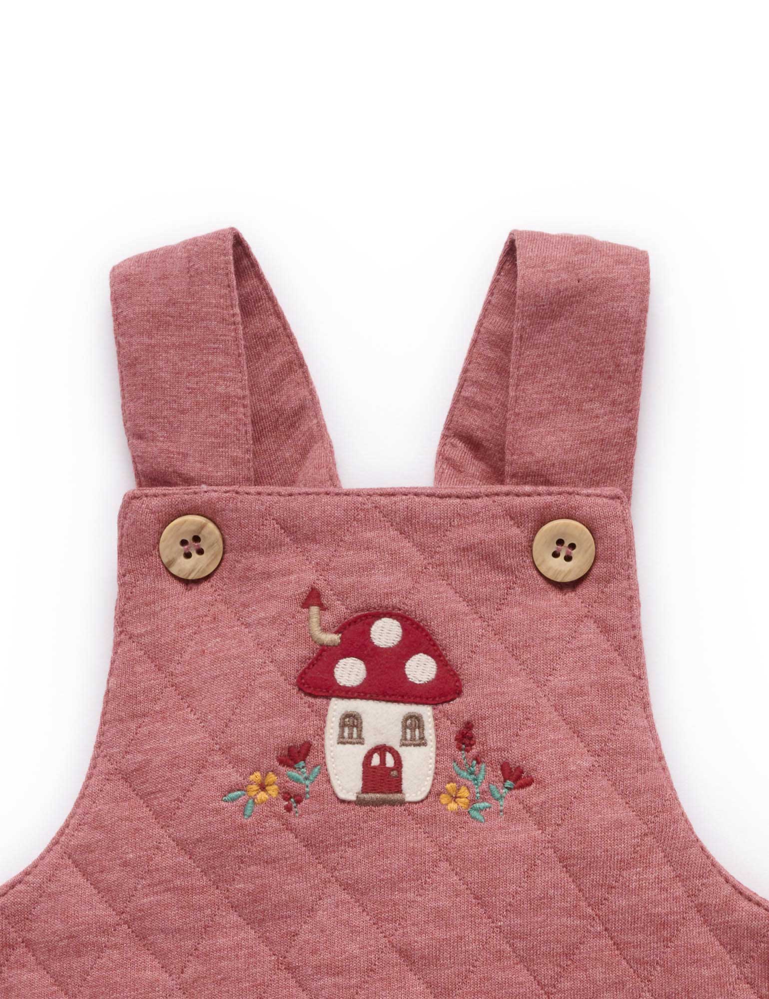 Pink quilted dress with mushroom design and buttons on a white background