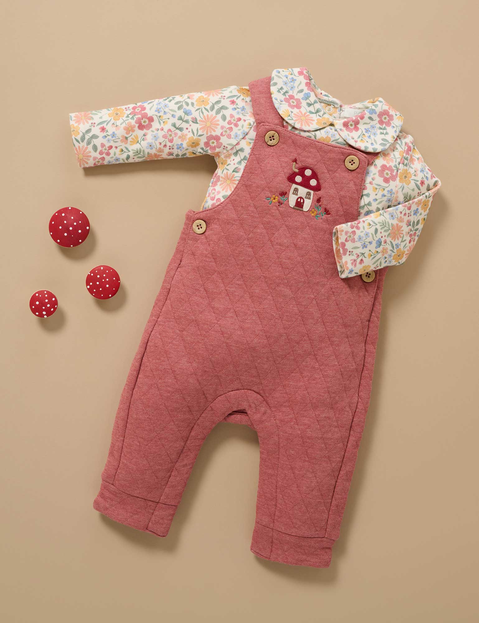 Pink baby romper with floral shirt on a beige background