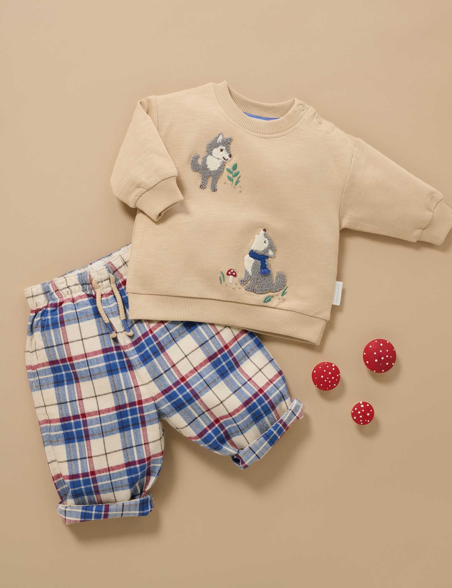 Children's outfit with beige sweatshirt and plaid pants on a beige background