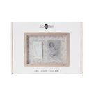A white rectangular gift box for a baby keepsake photo frame set by Petit Maitre Chaut. The front of the box features a clear window displaying a light wood frame with two sample inserts: a white baby footprint print and a black-and-white newborn photo.