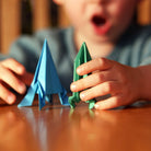 Child holding blue and green paper triangles on a wooden table
