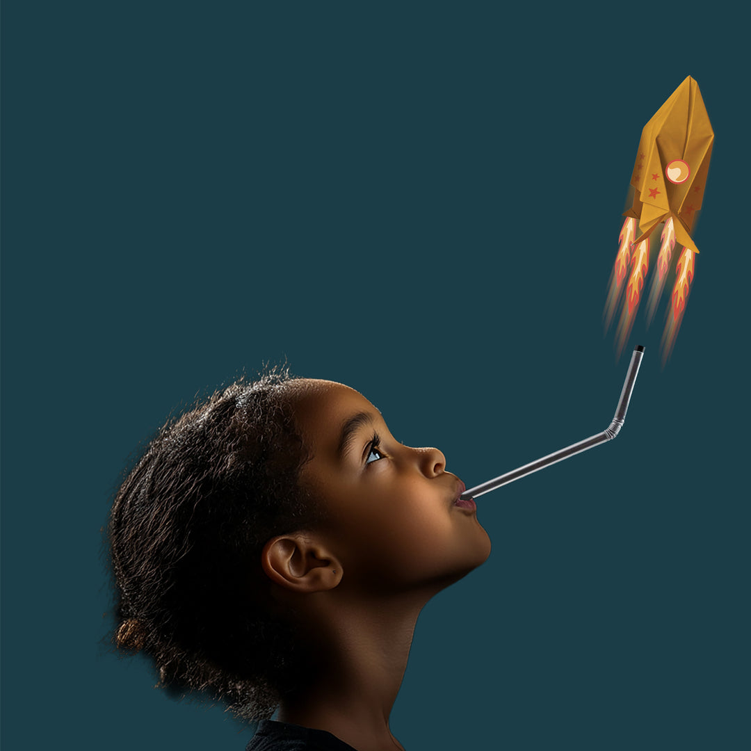 Child blowing on a paper rocket with flames against a dark background