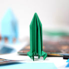 Green origami rocket ship on a blurred background