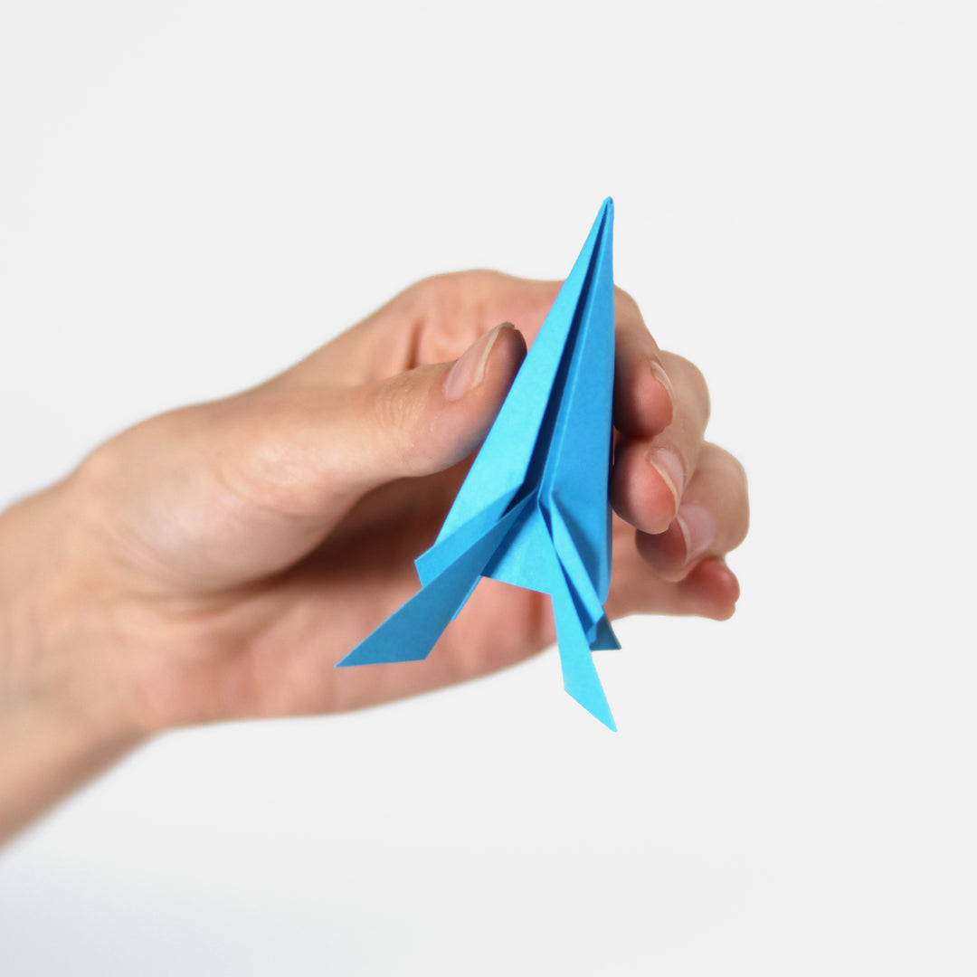 Hand holding a blue paper airplane against a white background