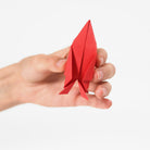 Hand holding a red origami airplane against a white background