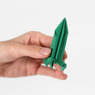Hand holding a green origami object against a white background