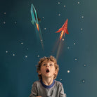 Child looking up at toy rockets against a starry night sky