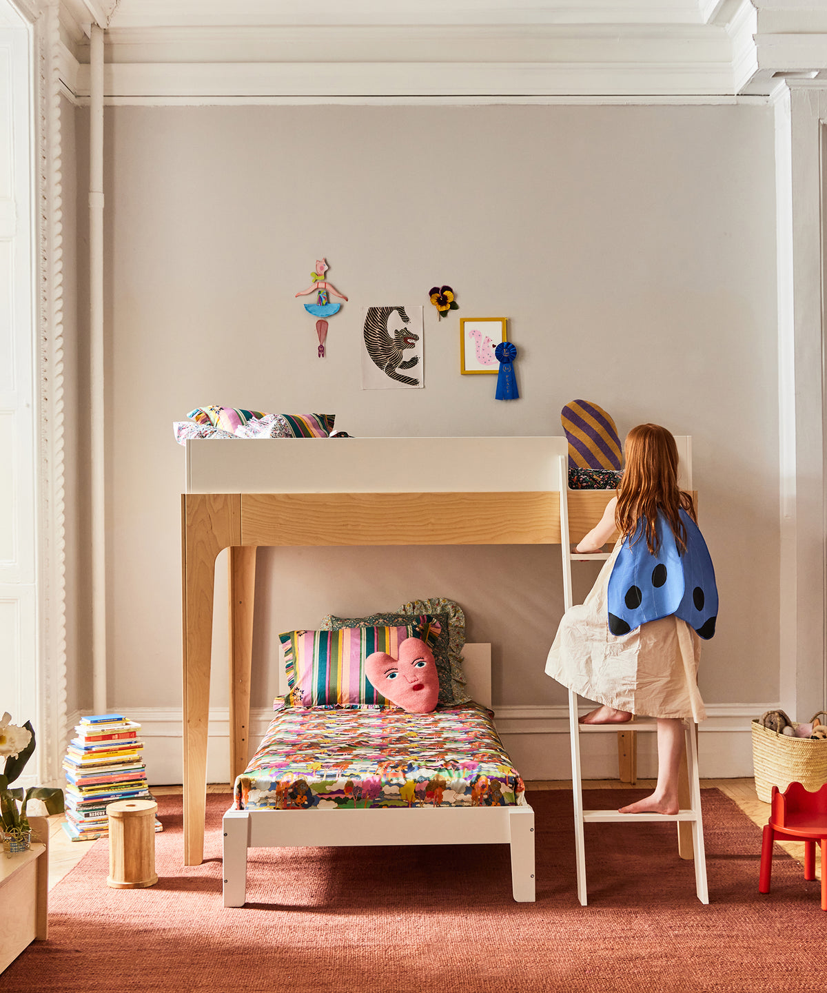 Child in a butterfly costume climbing a ladder to a loft bed in a child's bedroom.