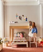 Child in a butterfly costume climbing a ladder to a loft bed in a child's bedroom.