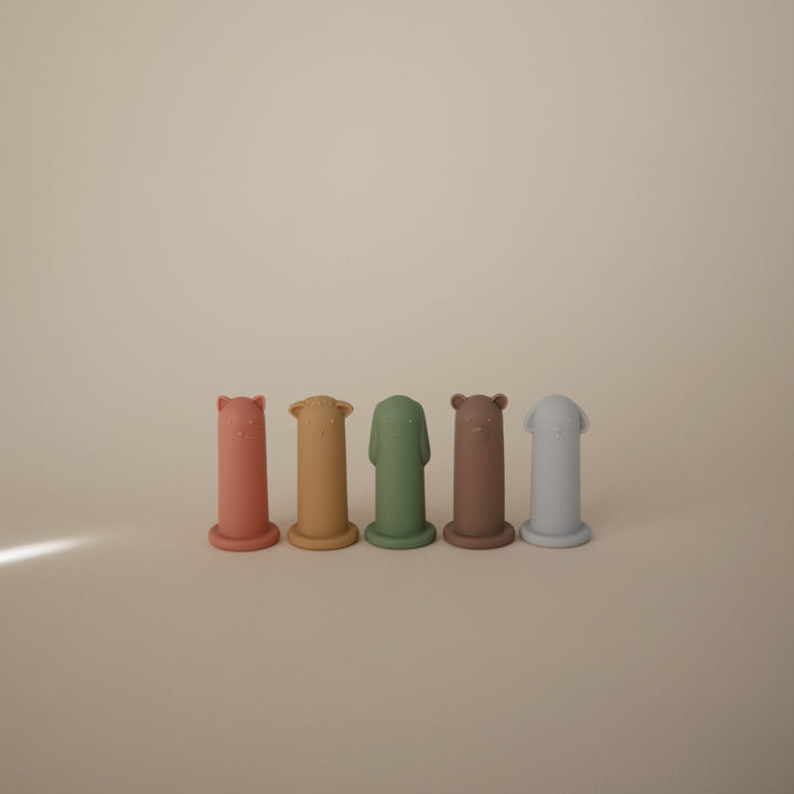 Five cylindrical figurines in different colors arranged on a beige surface.