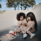 Two children playing with toys on a concrete surface outdoors.