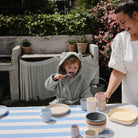 Woman and child at a table with ceramic items outdoors