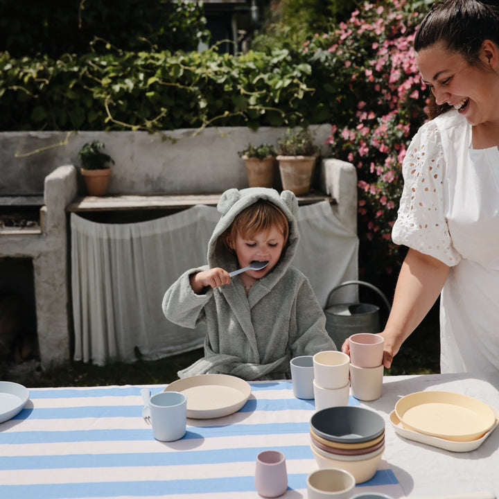 Woman and child at a table with ceramic items outdoors