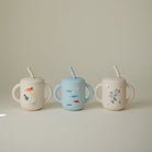 Three children's sippy cups with animal illustrations on a neutral background