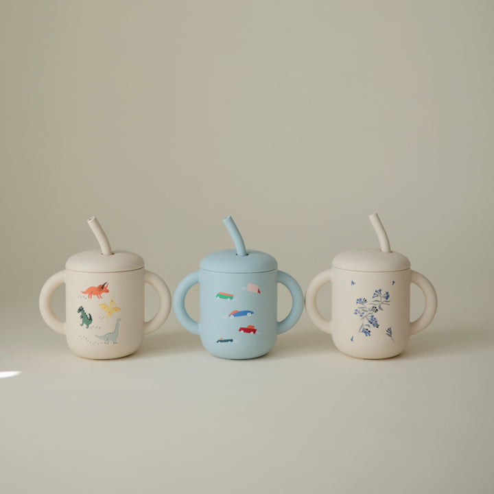 Three children's sippy cups with animal illustrations on a neutral background