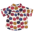 A short-sleeve baby shirt with an all-over pattern of colorful hand-drawn apples in red, blue, and mustard yellow on an off-white background.