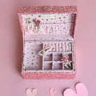 Pink jewelry box with jewelry on a pink background