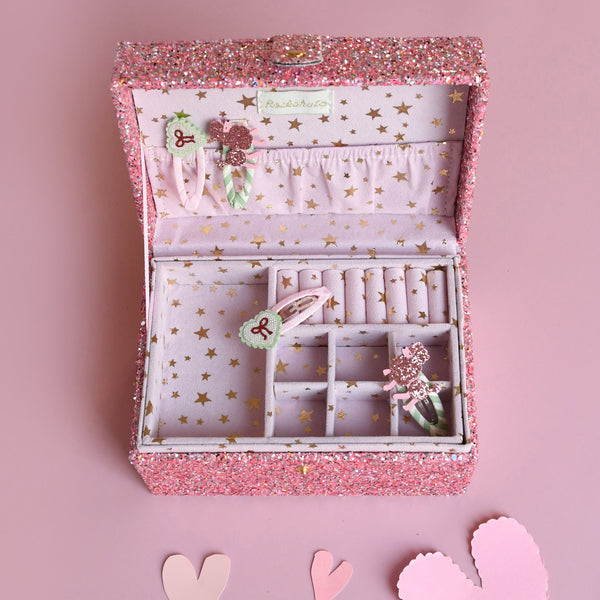 Pink jewelry box with jewelry on a pink background