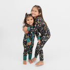 Two children wearing matching pajamas with animal prints on a white background