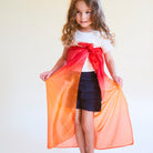 Young girl holding an orange and red fabric against a white background
