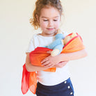 Child holding a baby模拟器 and a toy with an orange blanket against a white background