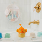 Orange fish-shaped bath toy on a bathtub ledge with bathroom fixtures in the background