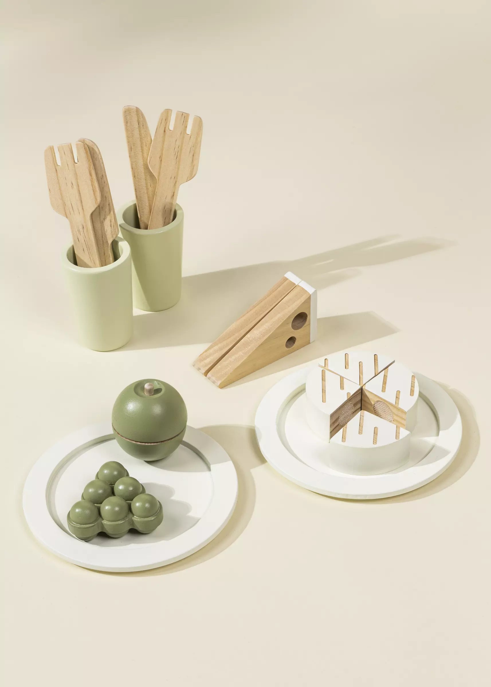 Set of wooden utensils in green holders on a beige background