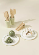 Set of wooden utensils in green holders on a beige background