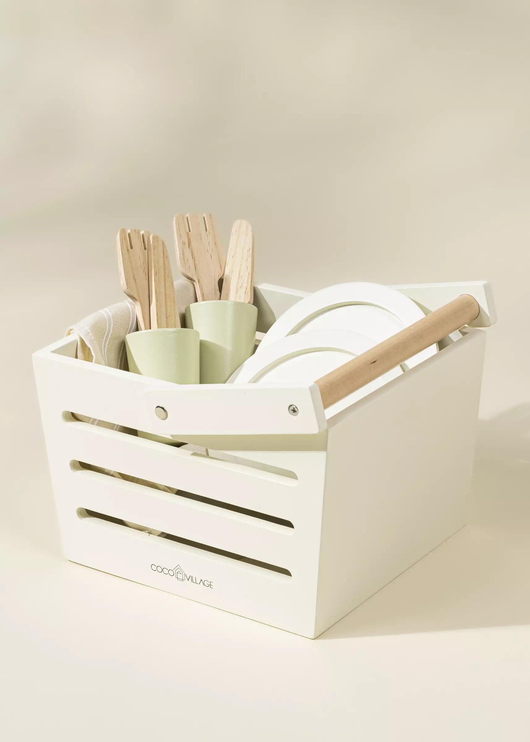 White storage crate with kitchen utensils including spatulas and a rolling pin on a beige background.