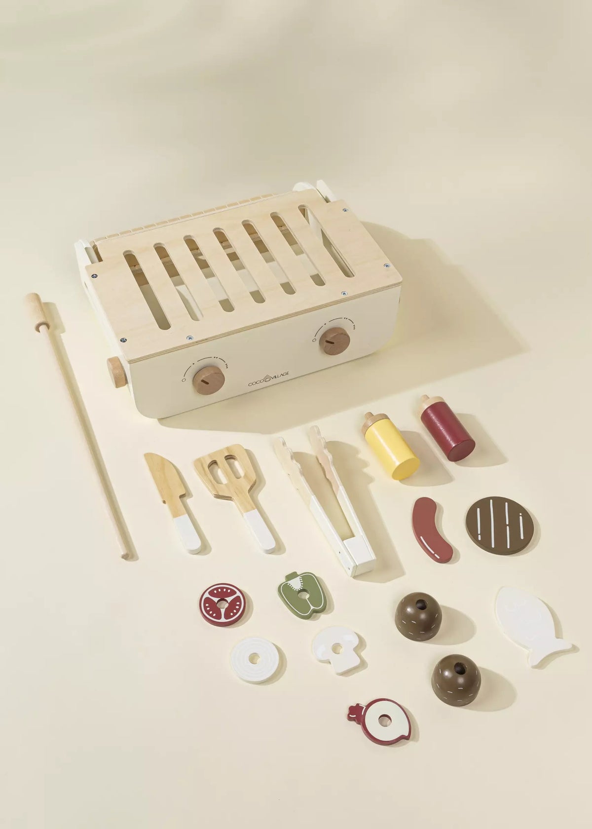 Wooden toy grill set with various accessories on a beige background